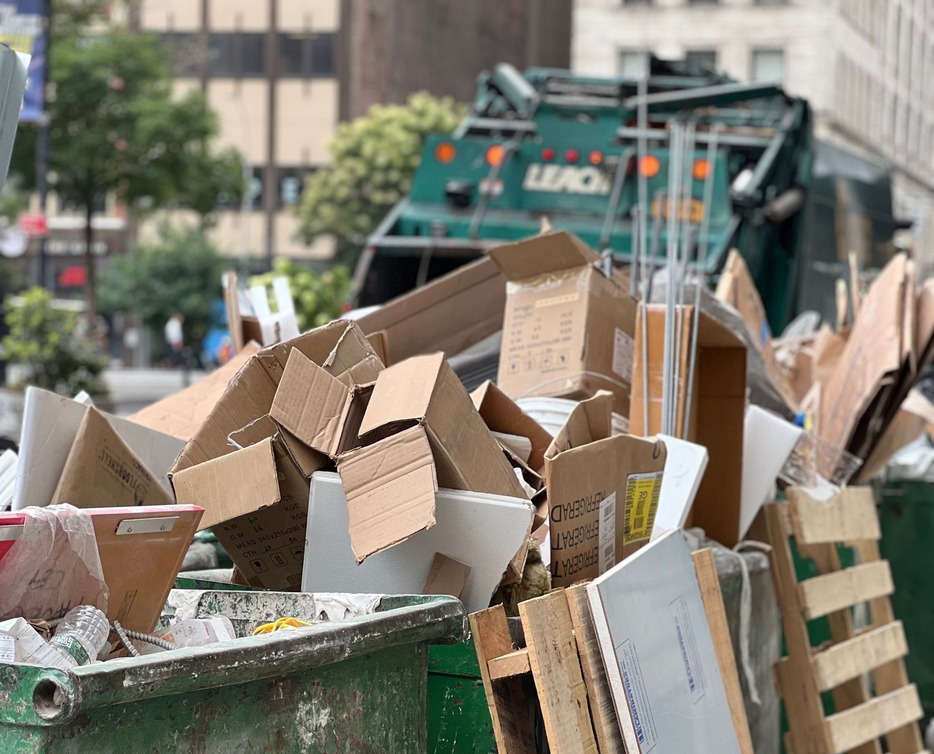 Piled cardboard boxes and waste in a city dumpster highlight urban recycling.